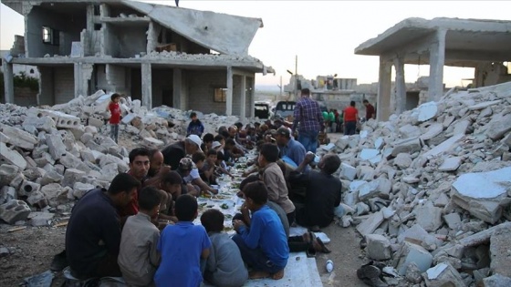 Suriye'de enkaz haline gelen evlerin arasında toplu iftar